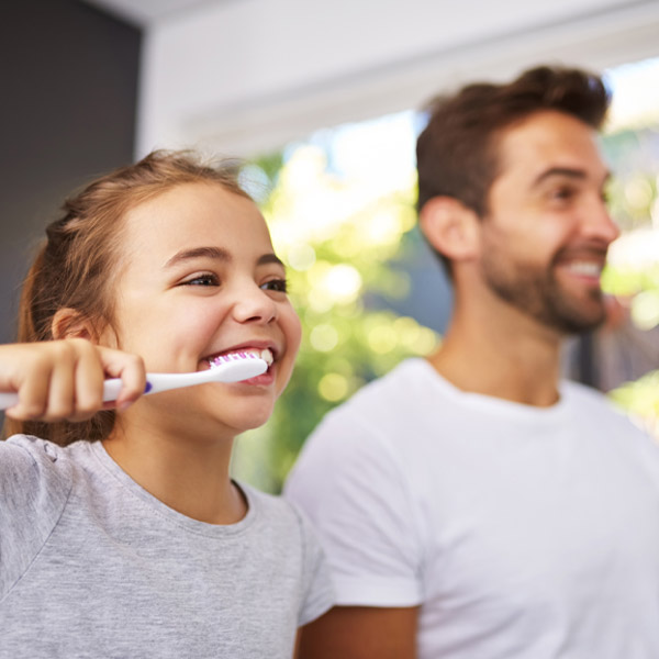father and daughter brushing their teeth